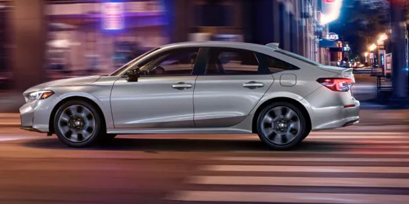 Silver 2026 Honda Civic Sedan driving through blurred streets near Tupelo, MS